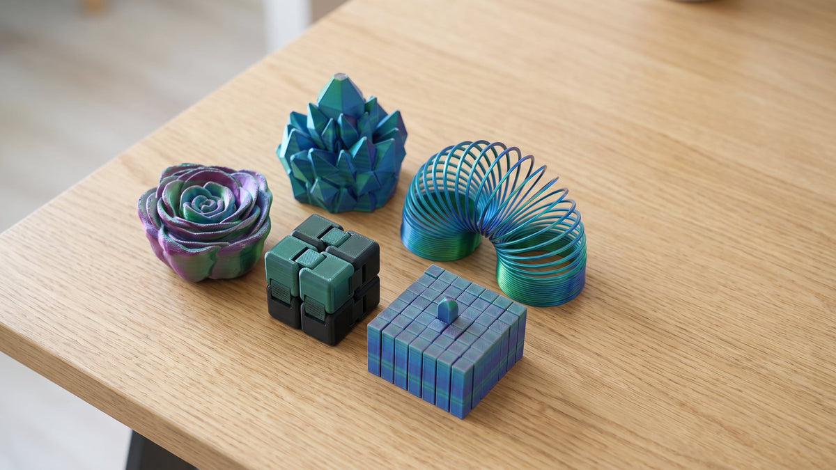 Assorted 3D printed fidget toys: a rose spinner, an infinity cube and spiral pass-through shapes