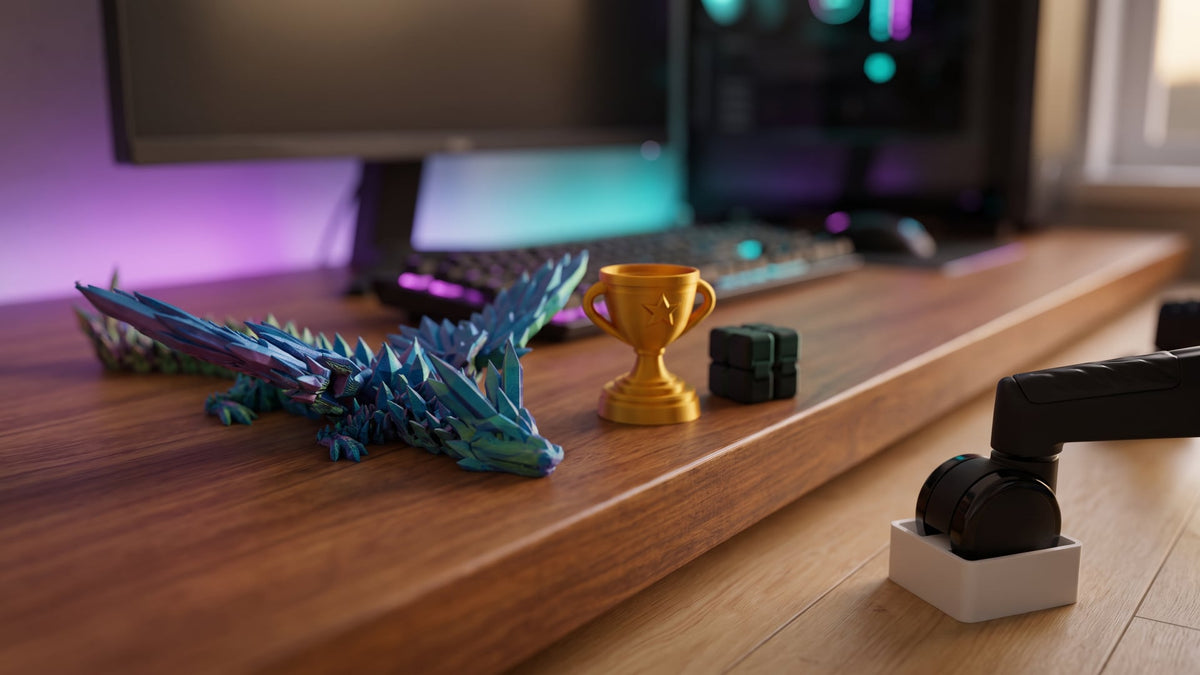 Gifts for gamers on a desk with RGB backlight: 3D printed winged dragon, gold mini trophy, Infinity Cube fidget, and a gaming chair caster in a white wheel stopper