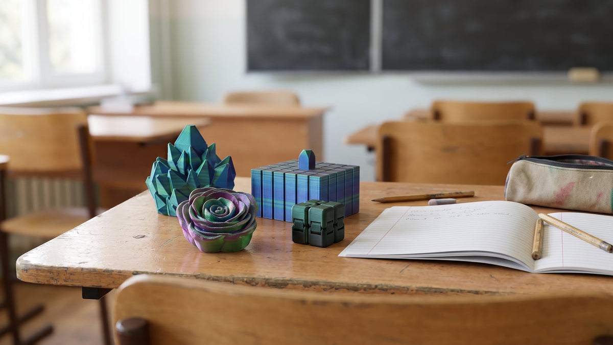 Quiet 3D-printed fidget toys for school on a desk: rose spinner, flexi grid and slime ball
